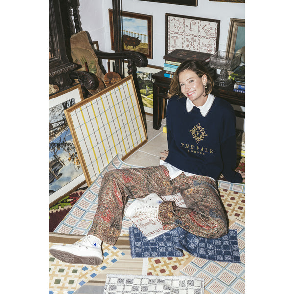 Embroidered Crewneck Sweater worn seated among The Vale London rug samples