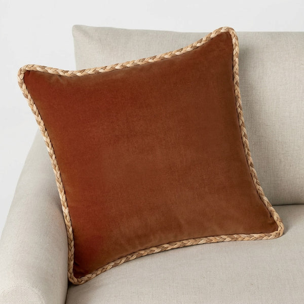 #all Rust velvet cushion trimmed with Fletta raffia braided cord, styled on a linen sofa