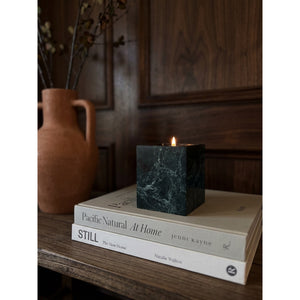 Jade Candle burning on a stack of design books beside a terracotta vase