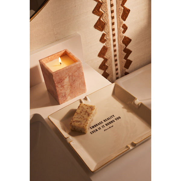Rose Quartz Candle lit on a vanity beside a Pierre Bergé trinket dish