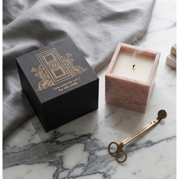 Pink marble vessel of the Rose Quartz Candle on grey silk with a brass wick trimmer